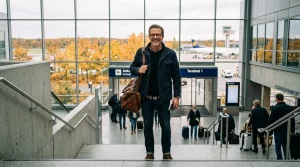 Mann mit Rucksack im Flughafenterminal, Herbst, Flugzeuge sichtbar