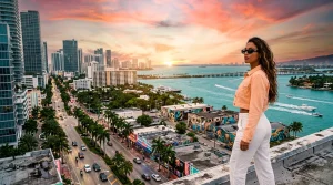 Frau bewundert Sonnenuntergang über Miami-Skyline und Meer