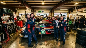 Rennfahrer und Team jubeln neben Rennwagen Nummer 18