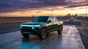 Grüner Rivian R1T Elektro-Pickup auf Straße mit Stadtskyline